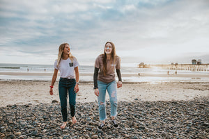 Teen girls walking on beach, laughing, and wearing colorful Nozscreen on their noses.